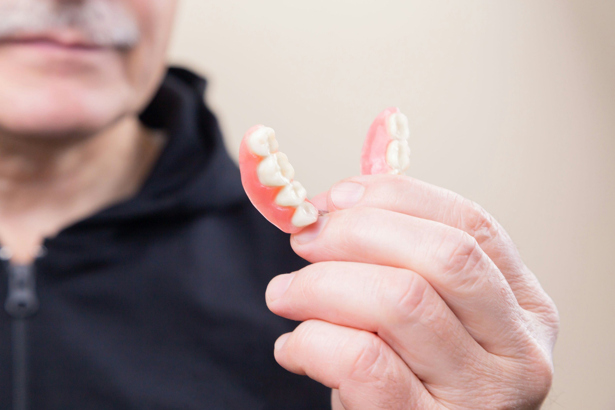 old person holding dentures