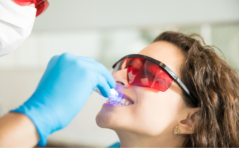 doctor whitening teeth of woman
