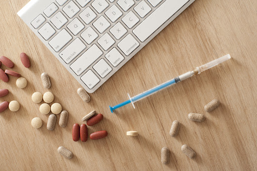 tablets, capsules and injections presentation on a table next to a keyboard