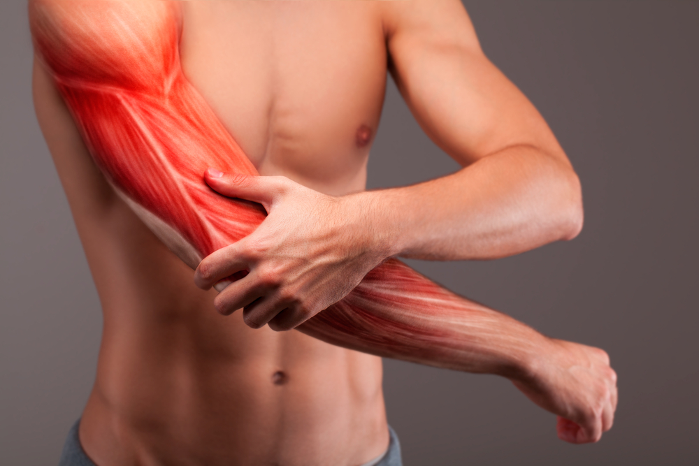 person holding his arm due to muscle cramps