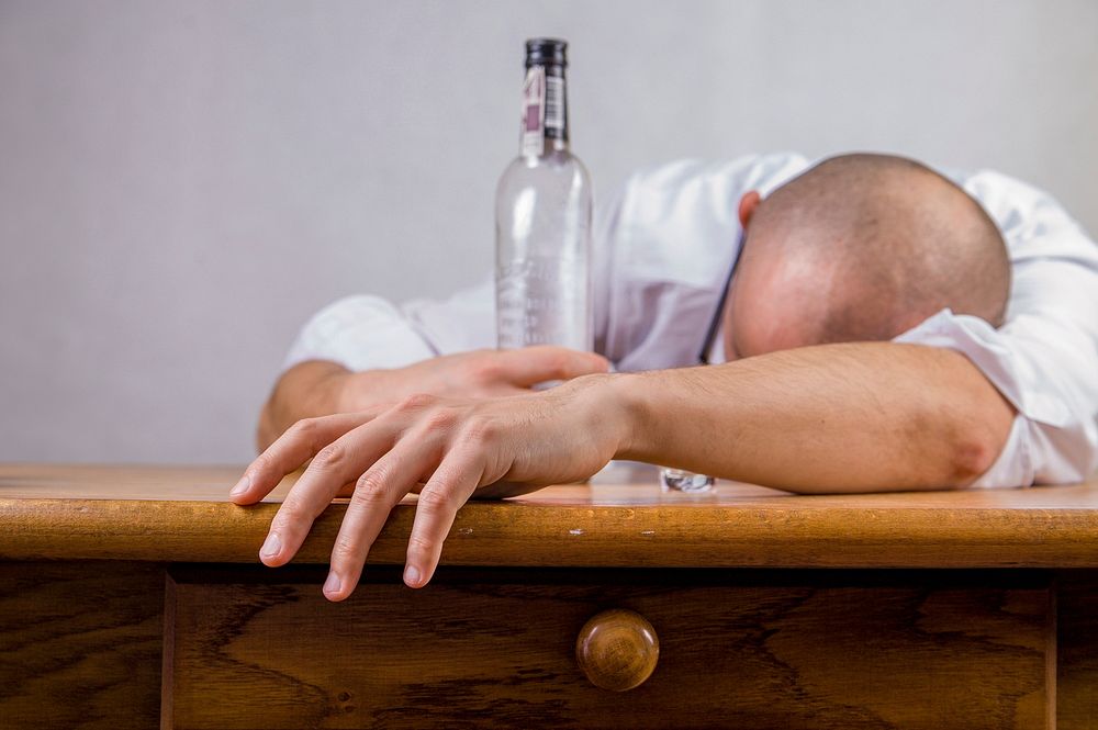 person with alcohol beside