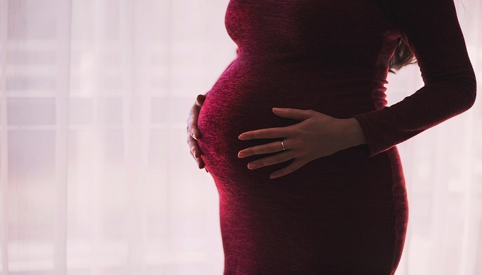 pregnant woman red dress holding belly