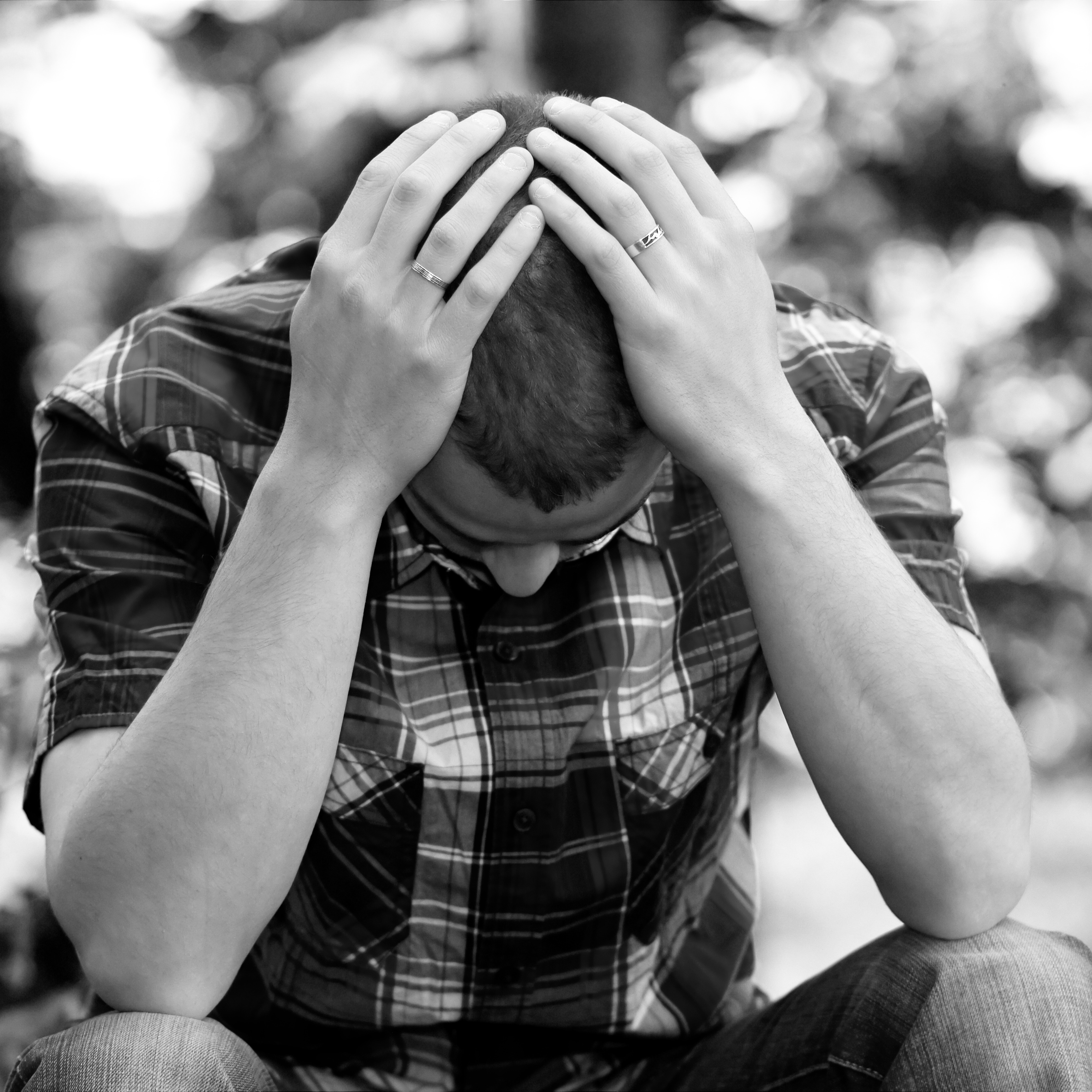 man black and white shirt depressed hands on head