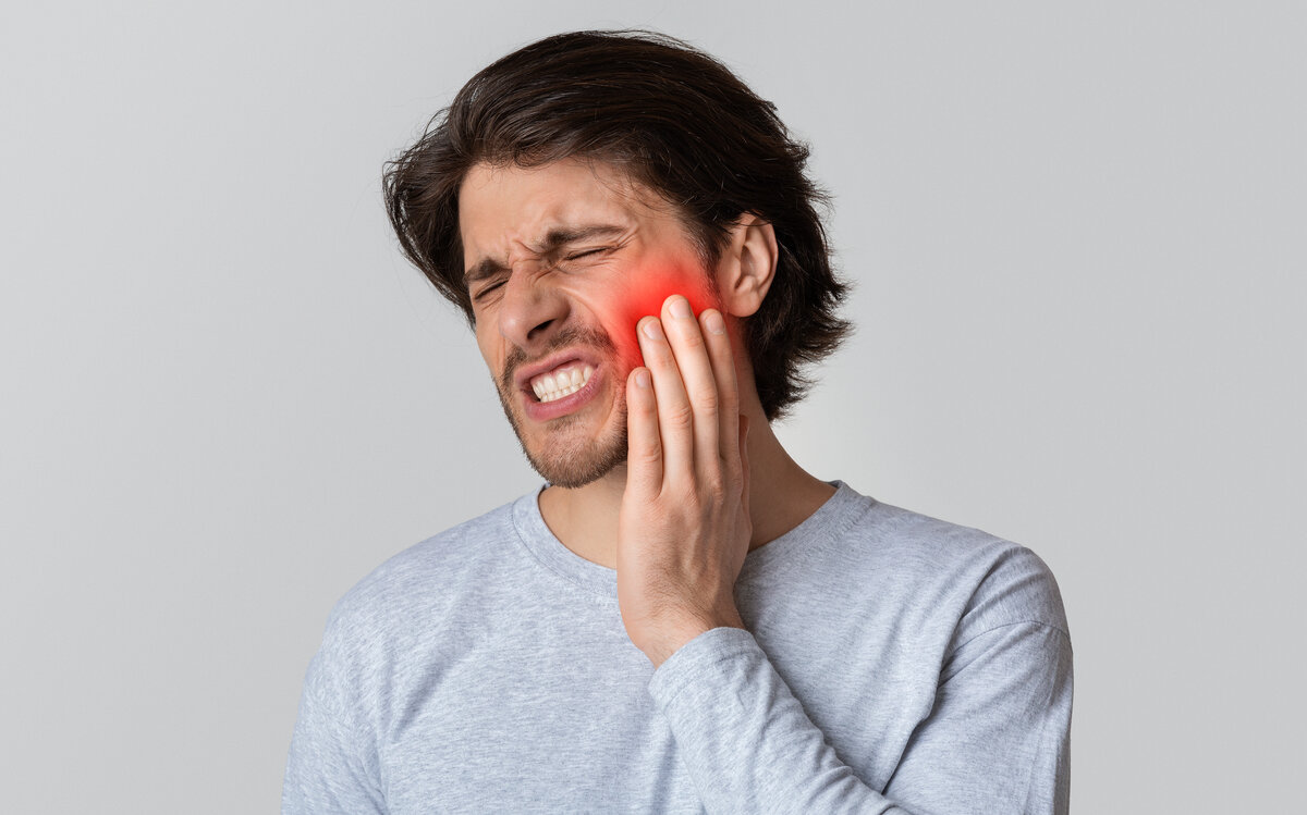 person holding cheek because of tooth pain