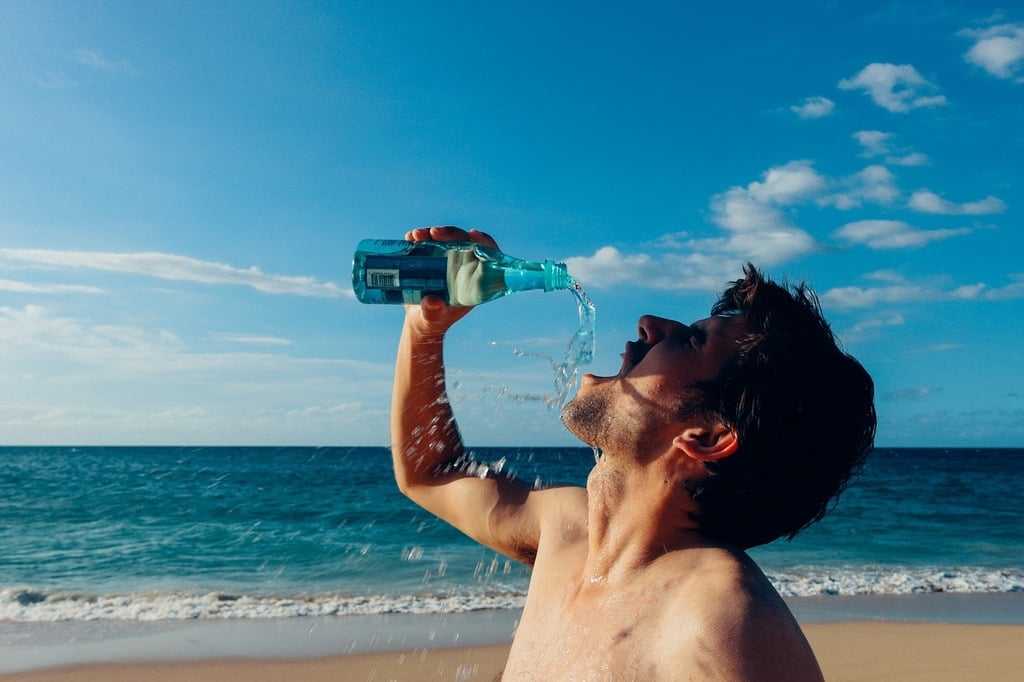 man on the beach drinking water