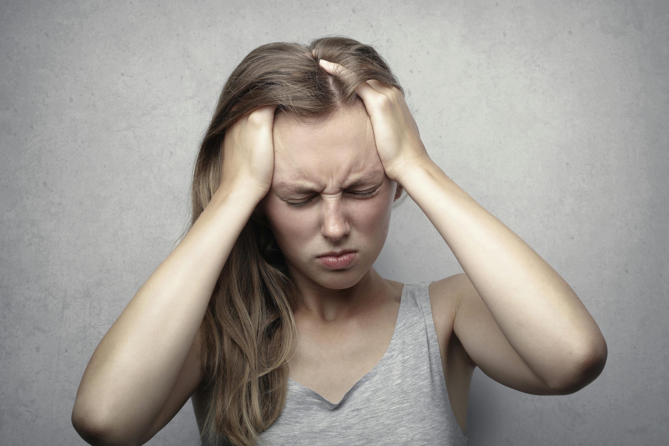 person with skull pressure hands on head 
