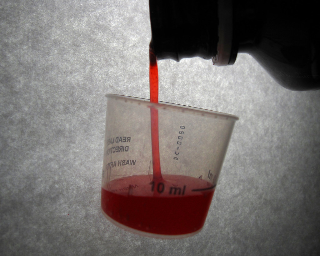 cough syrup being measured in a cup